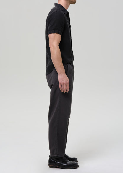 Man wearing a black button-up shirt and pants on a plain background
