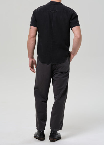 Man wearing a black button-up shirt and pants on a plain background