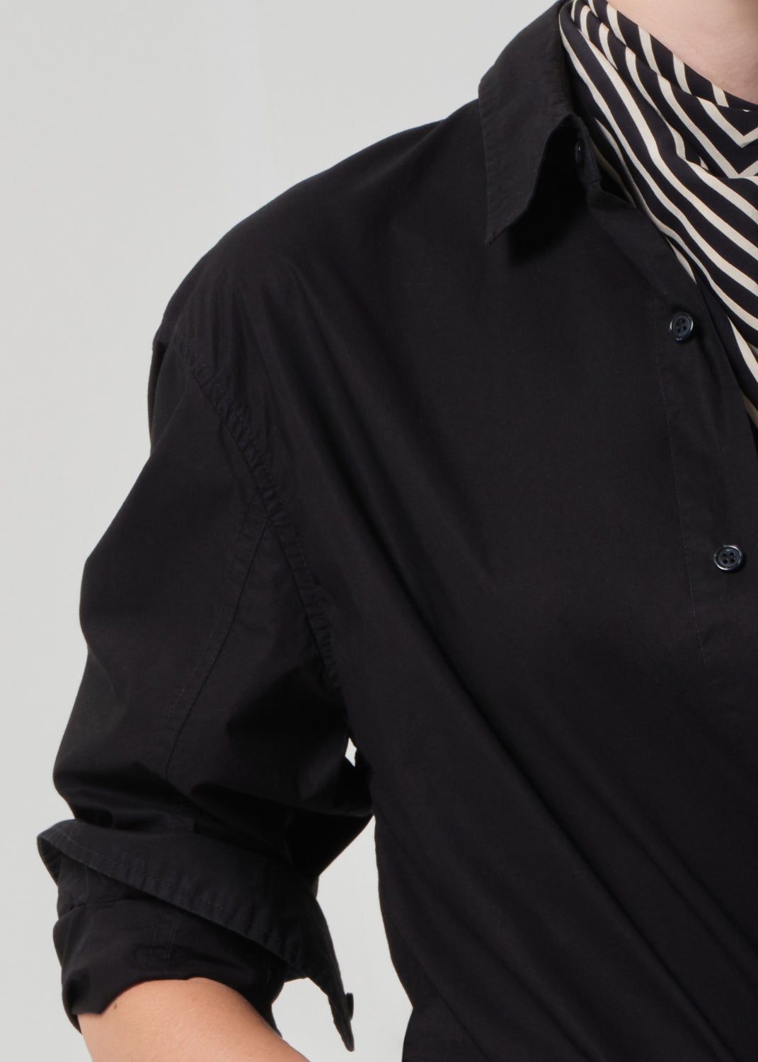 Black shirt with rolled-up sleeves and a zebra-striped scarf on a gray background