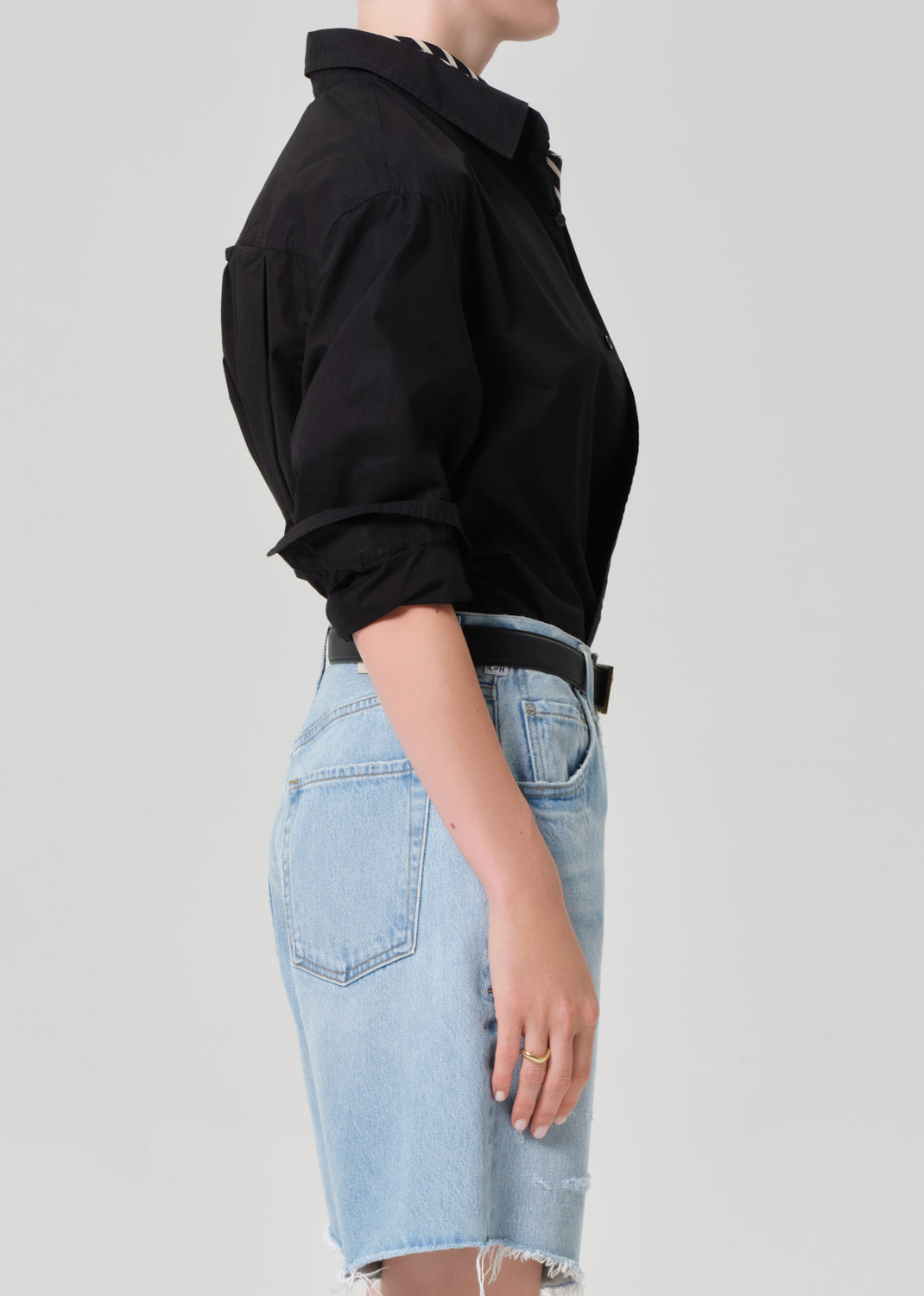 Person wearing a black shirt and light blue denim skirt on a plain background