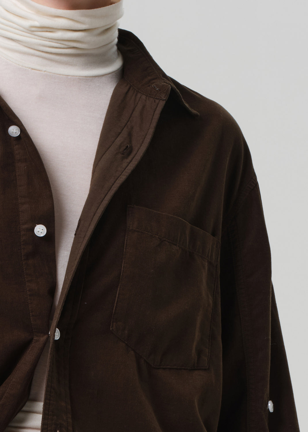 Brown shirt over a white turtleneck on a plain background