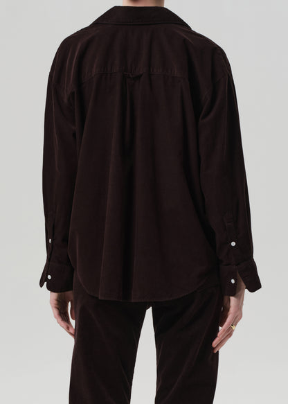 Person wearing a dark brown shirt and pants on a light gray background