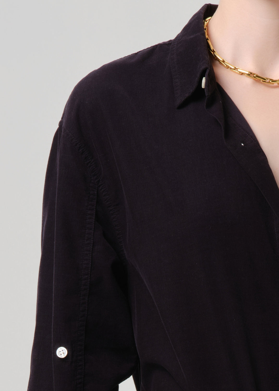 Dark grey shirt with a gold necklace on a grey background