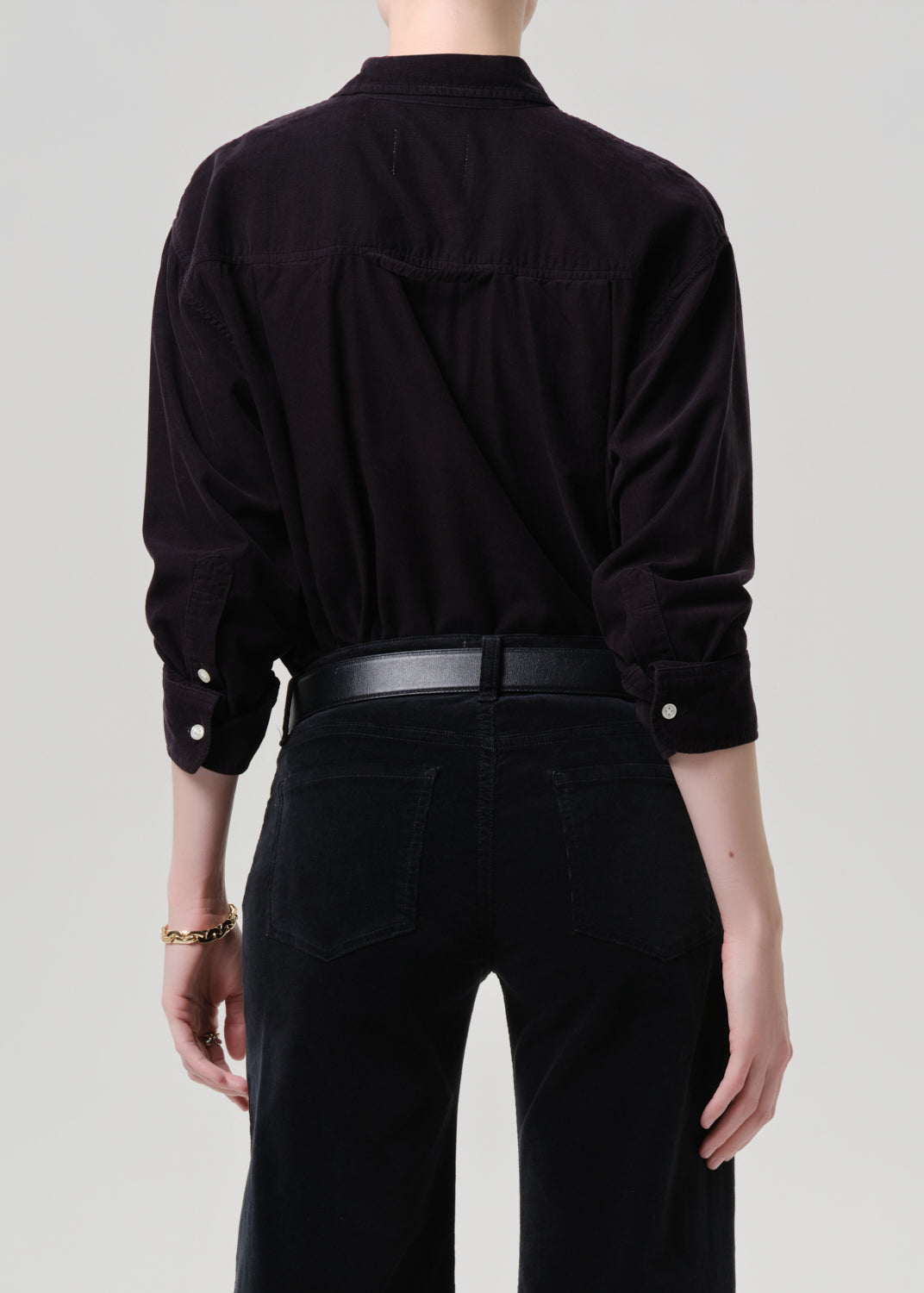 Person wearing a dark grey shirt and black pants on a grey background
