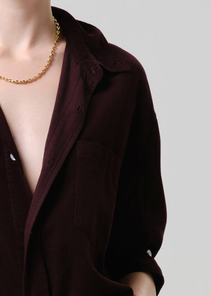 Purple shirt with a gold chain necklace on a grey background