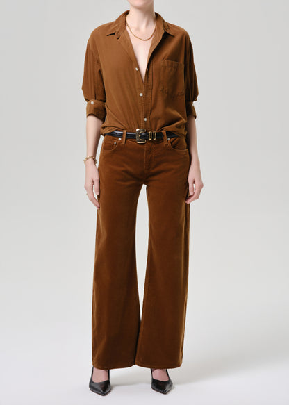 Person wearing a brown jumpsuit on a grey background