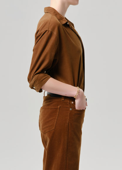 Person wearing a brown shirt and pants on a grey background