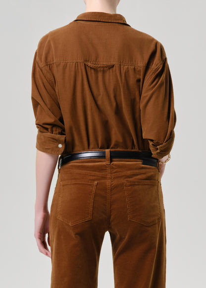Person wearing a brown shirt and pants on a grey background