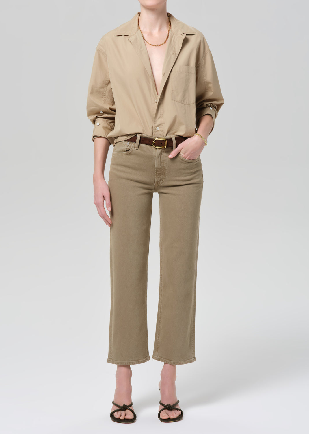 Person wearing a beige shirt and pants on a grey background