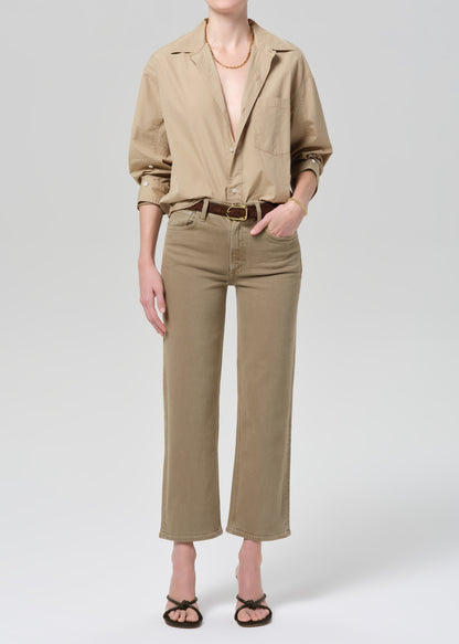 Person wearing a beige shirt and pants on a grey background