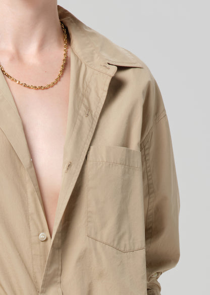 Beige shirt with a gold chain necklace on a plain background