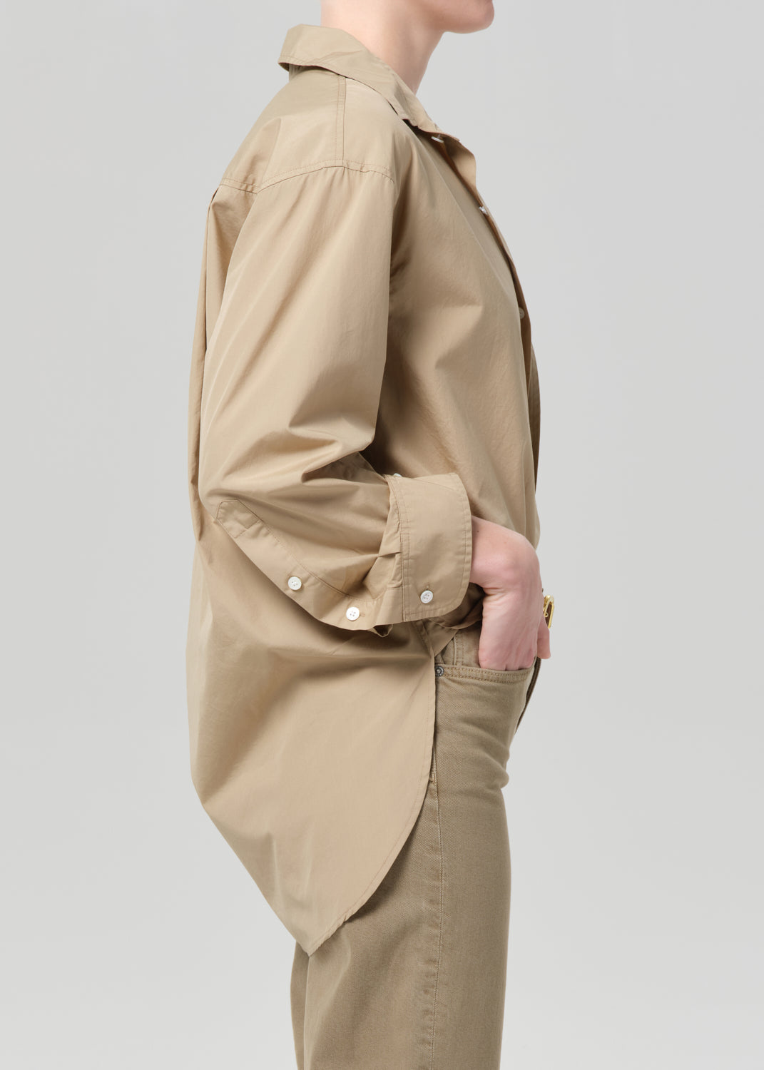 Person wearing a beige jacket and pants on a light gray background