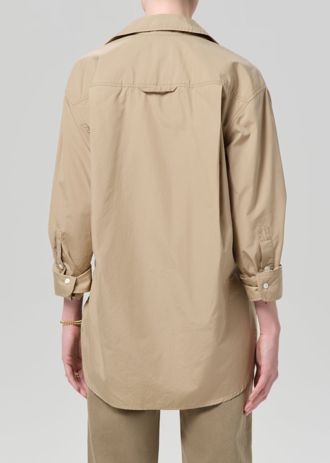 Person wearing a beige shirt and pants on a plain background