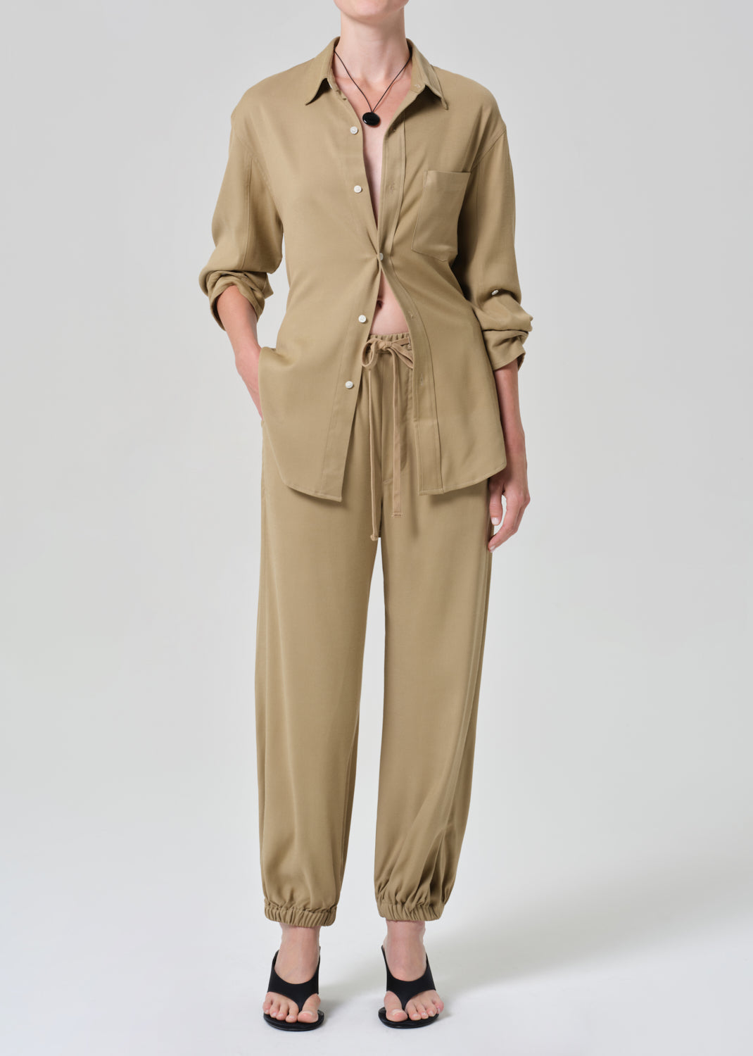 Person wearing a beige shirt and pants set on a plain background