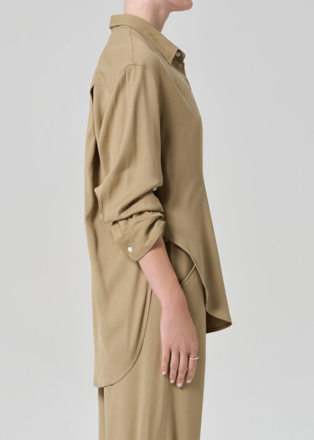 Person wearing a beige shirt and pants set on a plain background