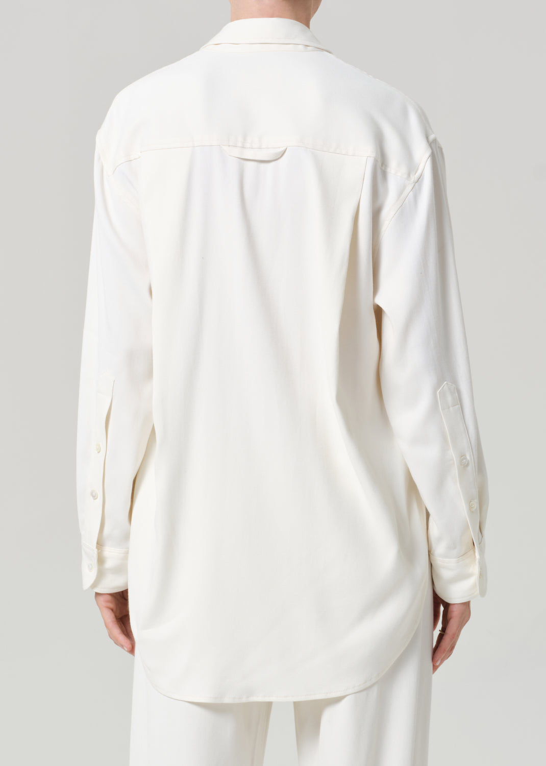 Person wearing an off-white shirt and pants on a gray background
