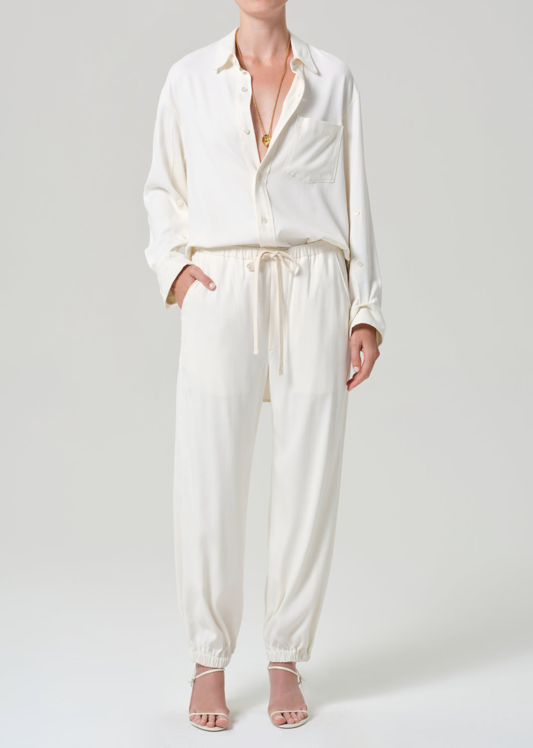 Person wearing an off-white shirt and pants on a gray background