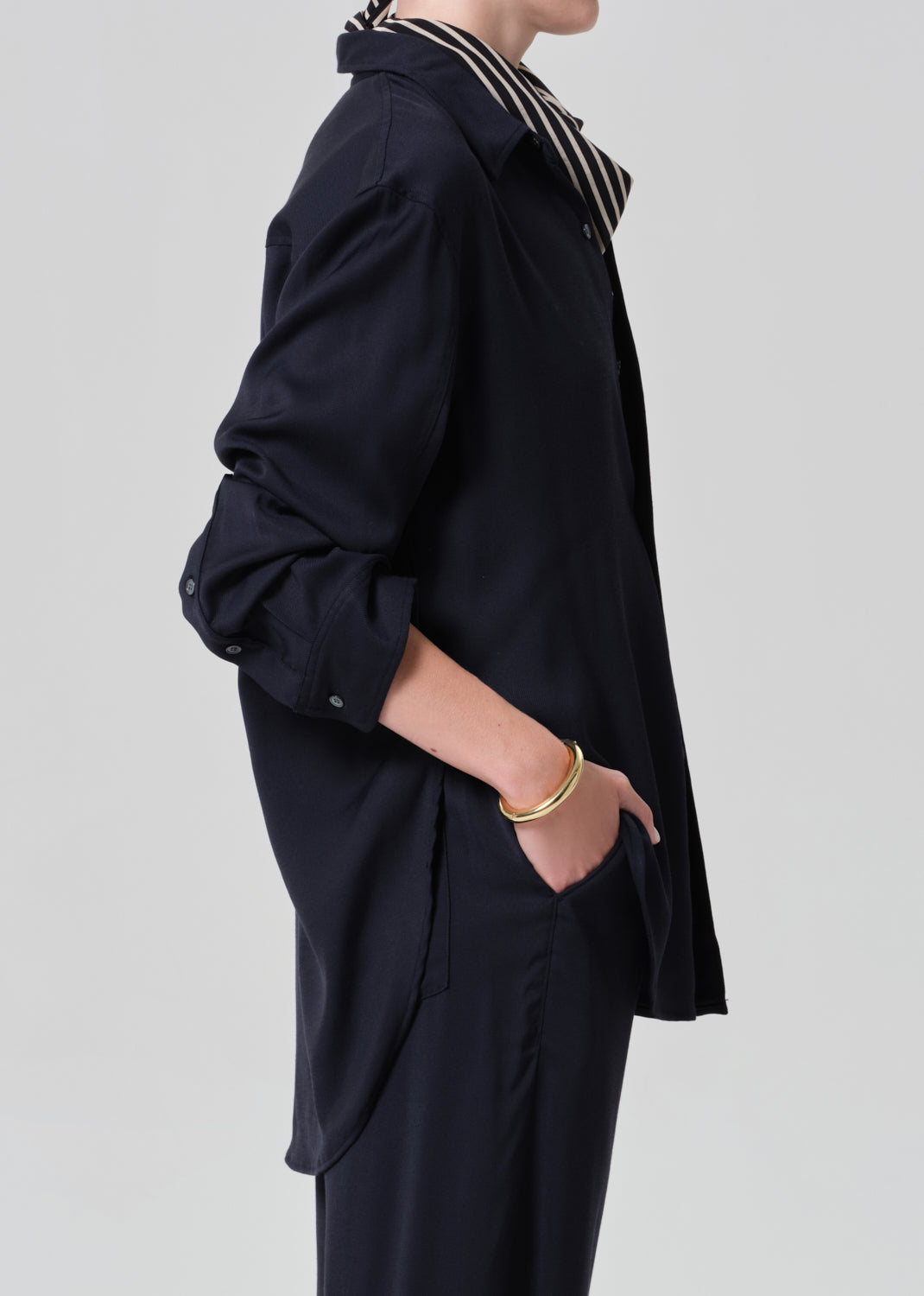 Person wearing a navy shirt and pants with a patterned scarf on a gray background