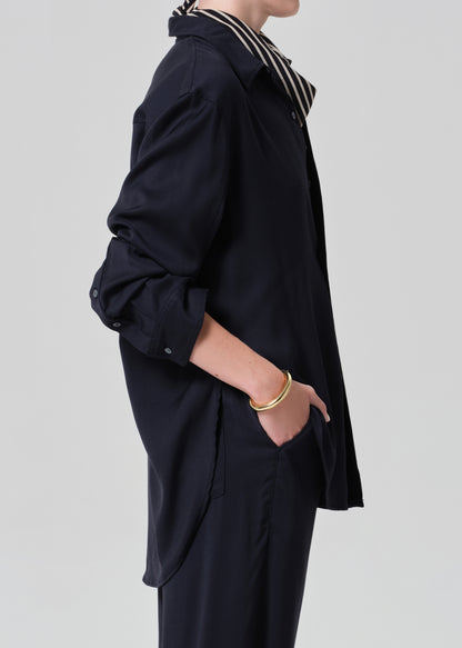 Person wearing a navy shirt and pants with a patterned scarf on a gray background