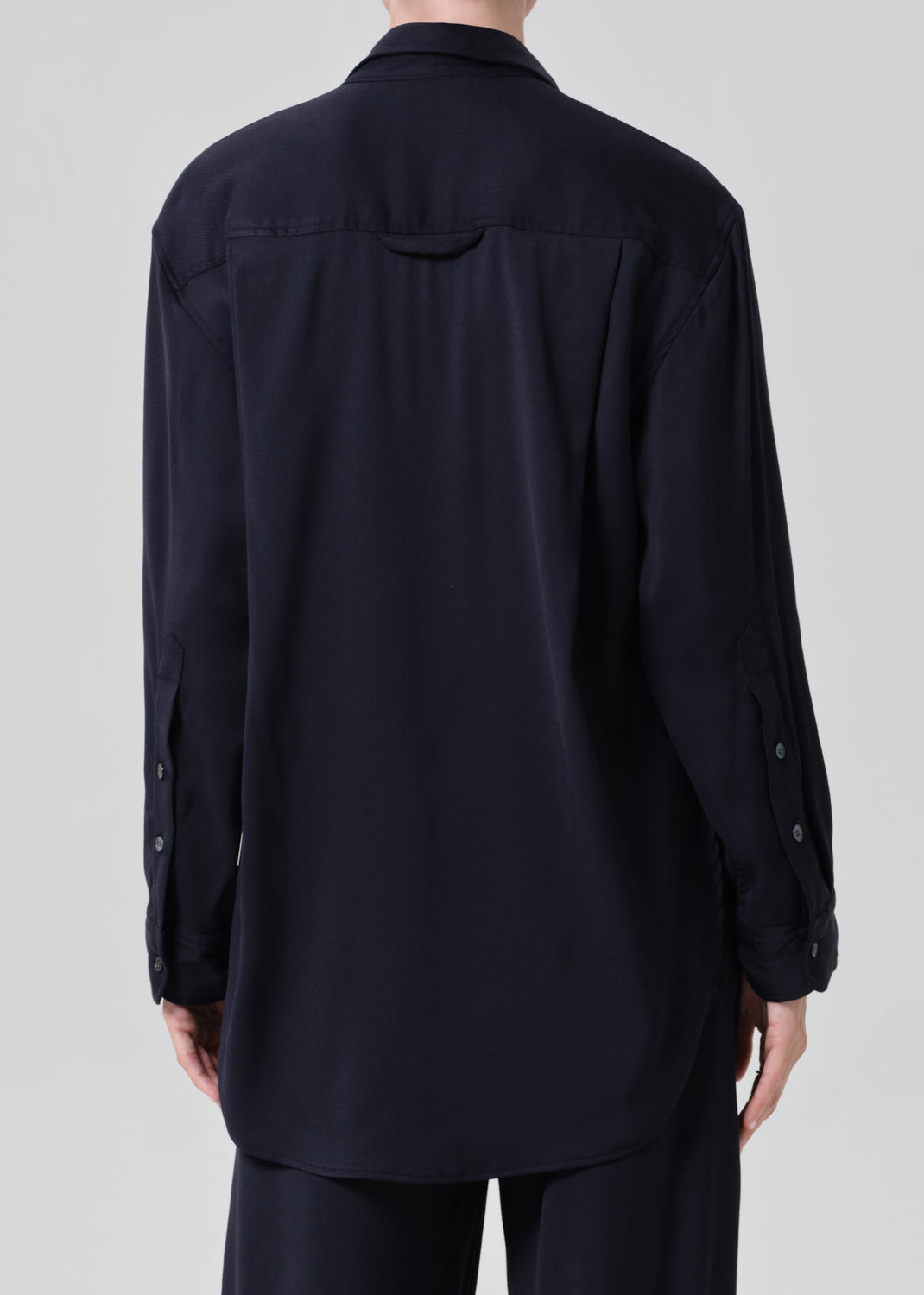 Person wearing a navy shirt and pants on a gray background