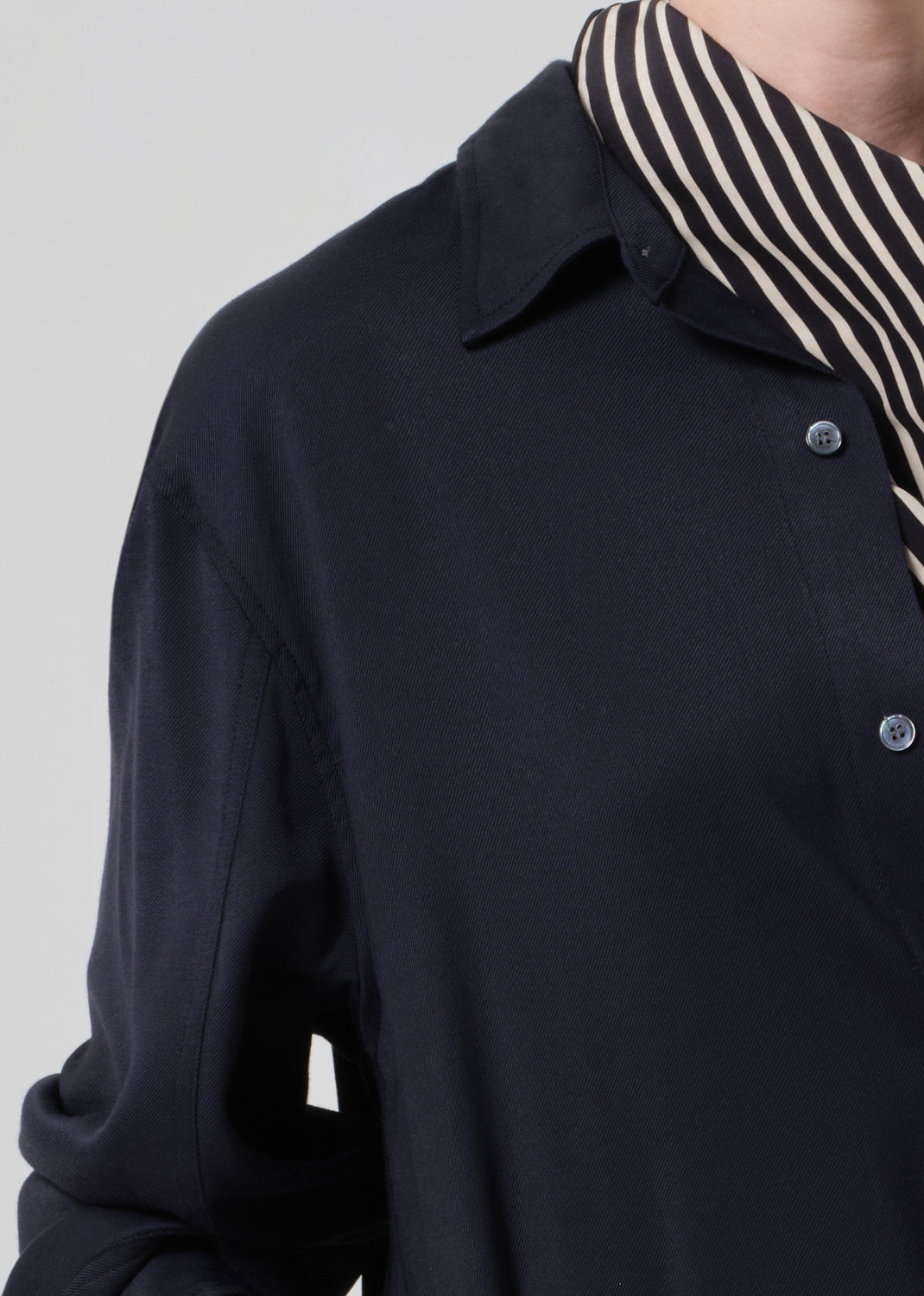 Person wearing a navy shirt with a patterned scarf on a gray background