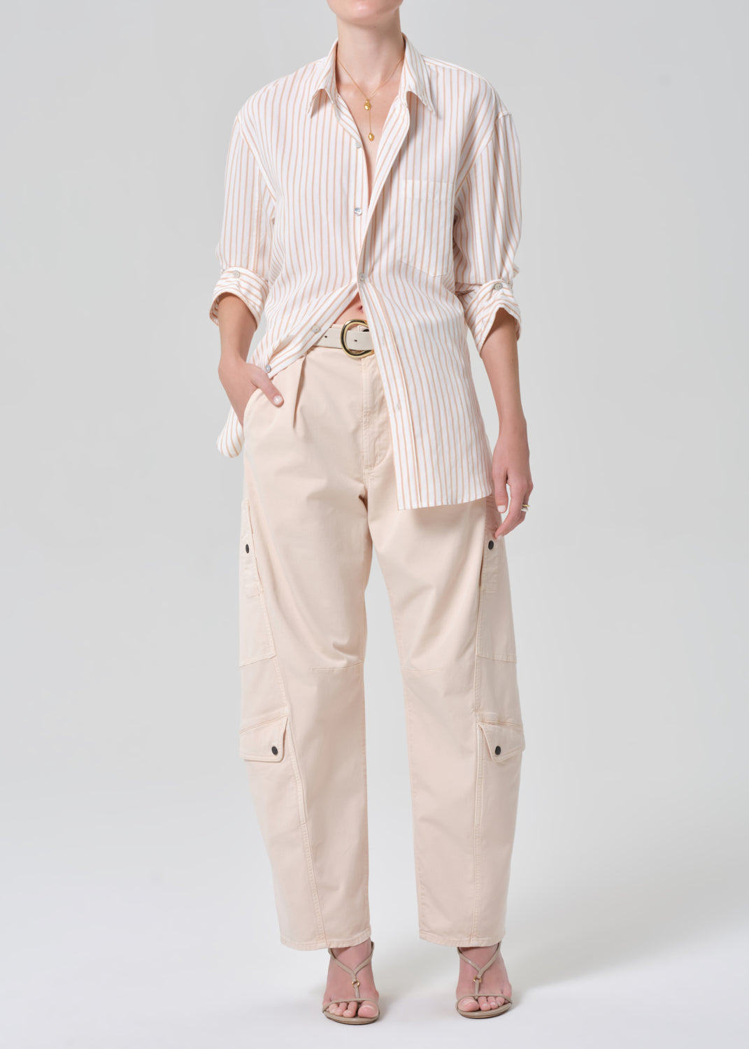 Person wearing a striped shirt and light pink pants on a plain background