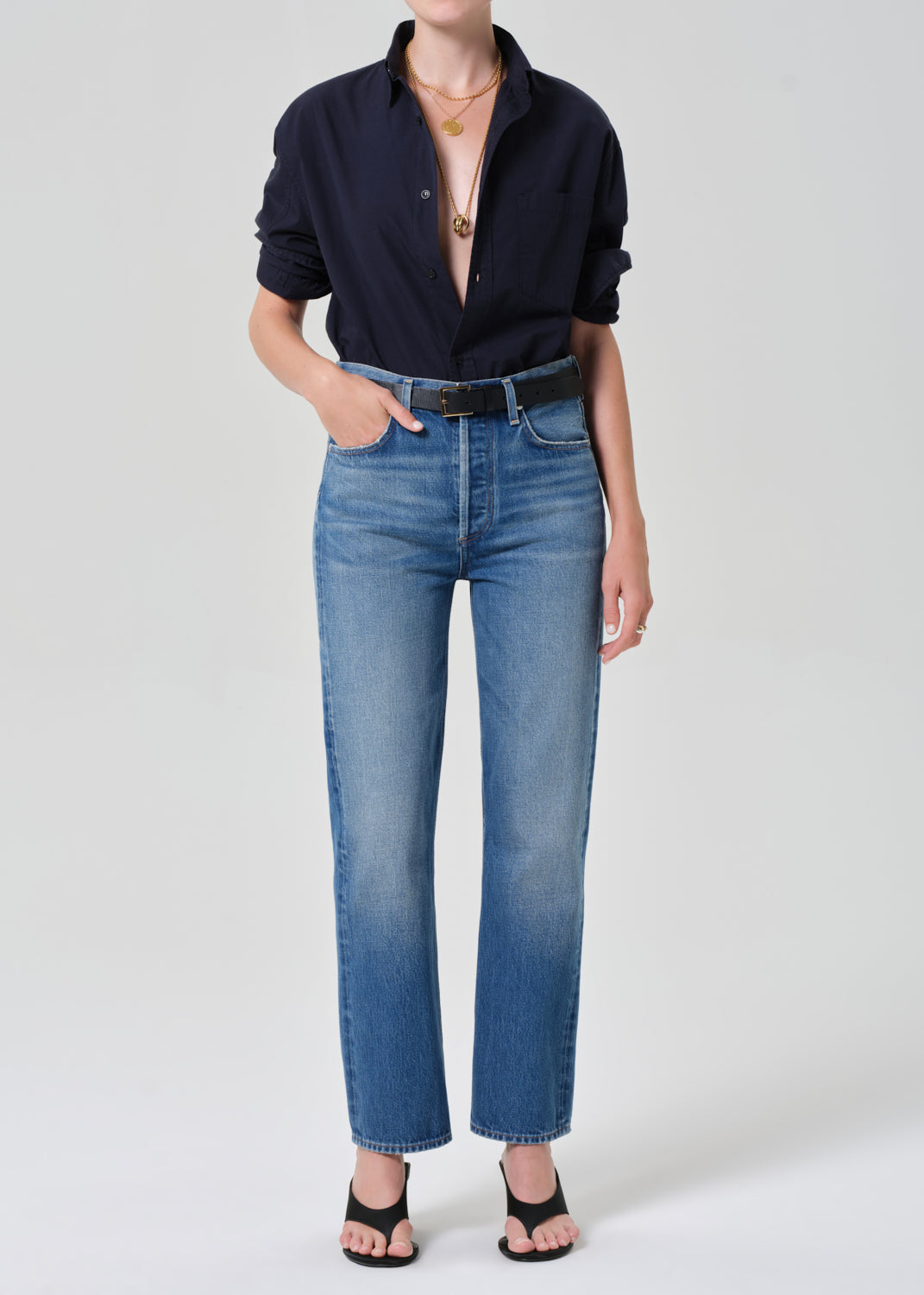 Person wearing a navy shirt and blue jeans on a plain background