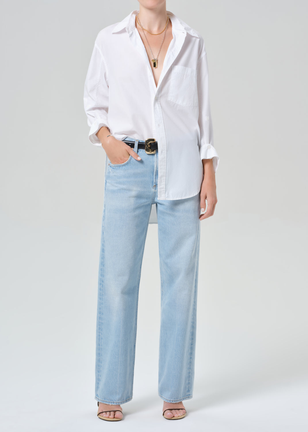 Person wearing a white shirt and light blue jeans on a plain background
