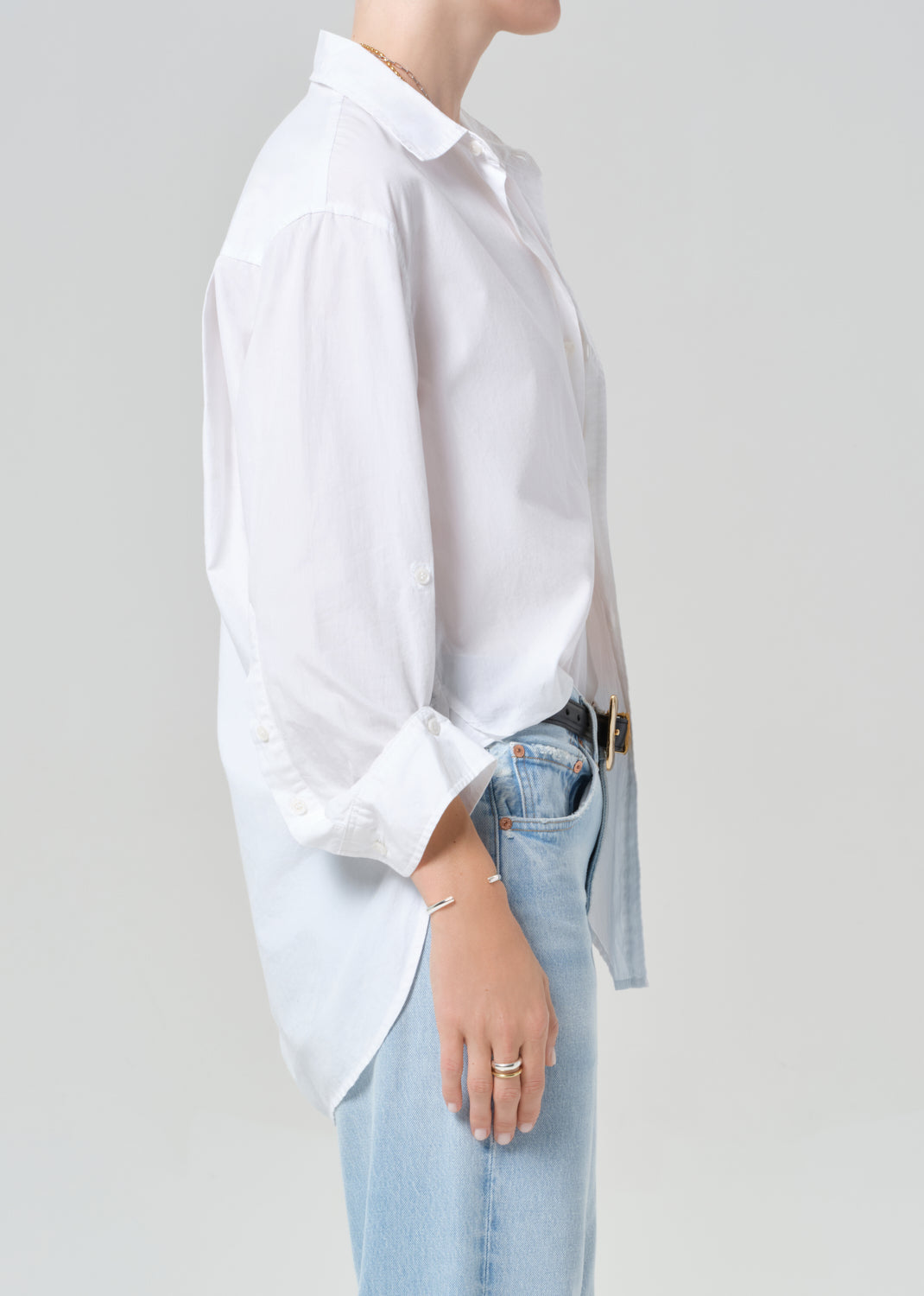 Person wearing a white shirt and light blue jeans on a plain background