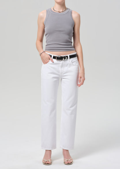 Person wearing a gray tank top and white pants on a plain background