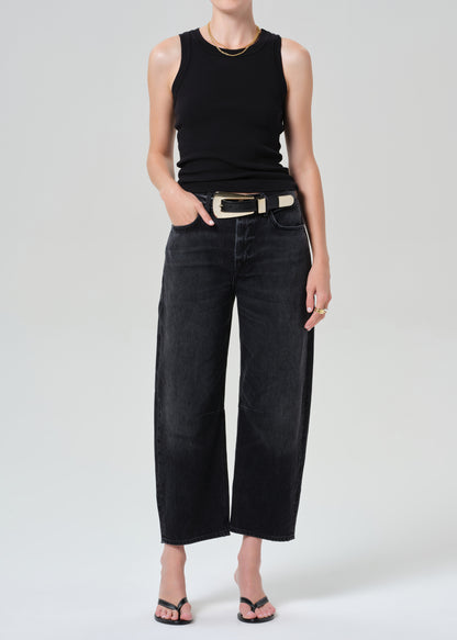 Person wearing a black sleeveless top and wide-leg black jeans on a white background