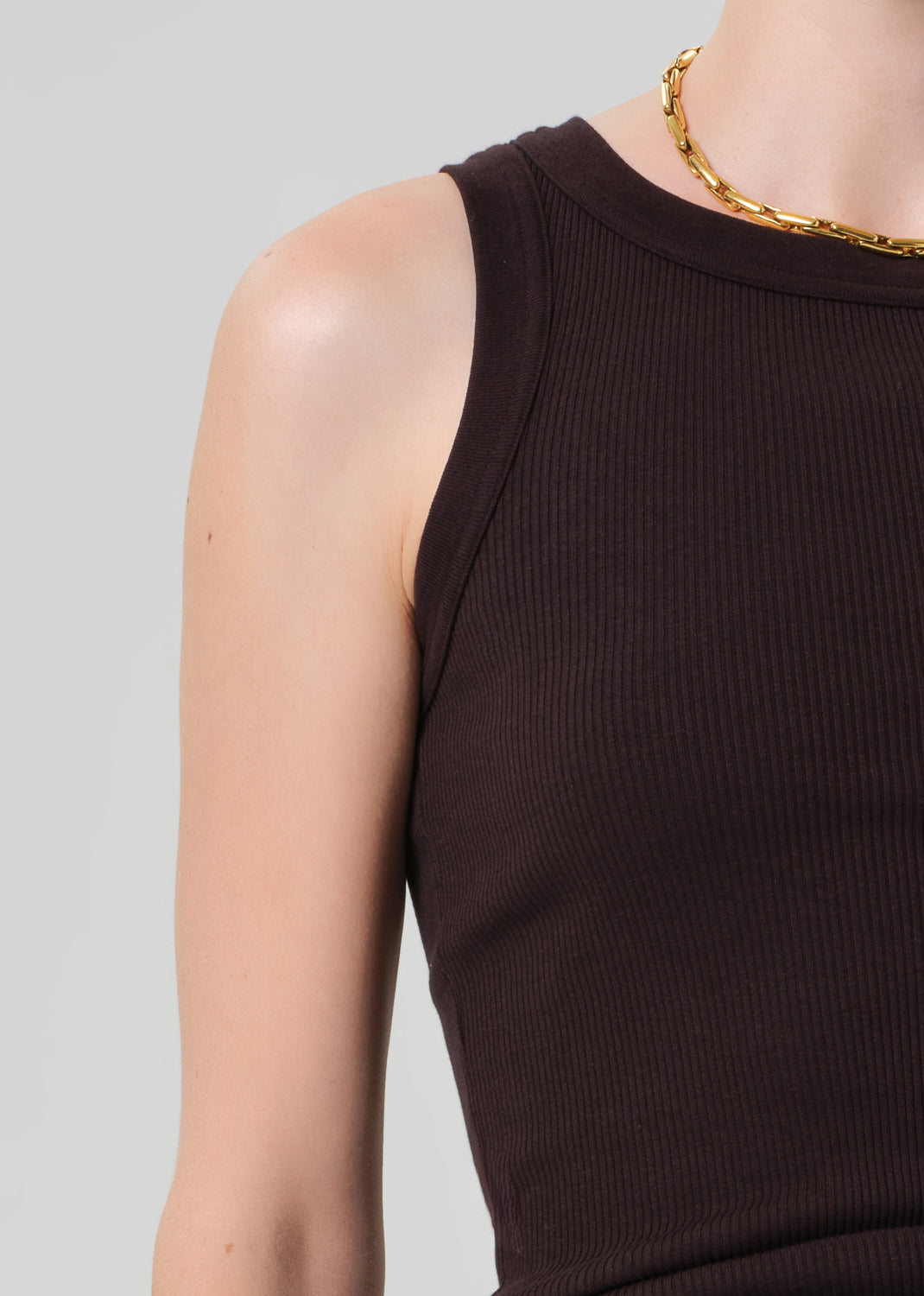 Person wearing a brown ribbed tank top with brown pants