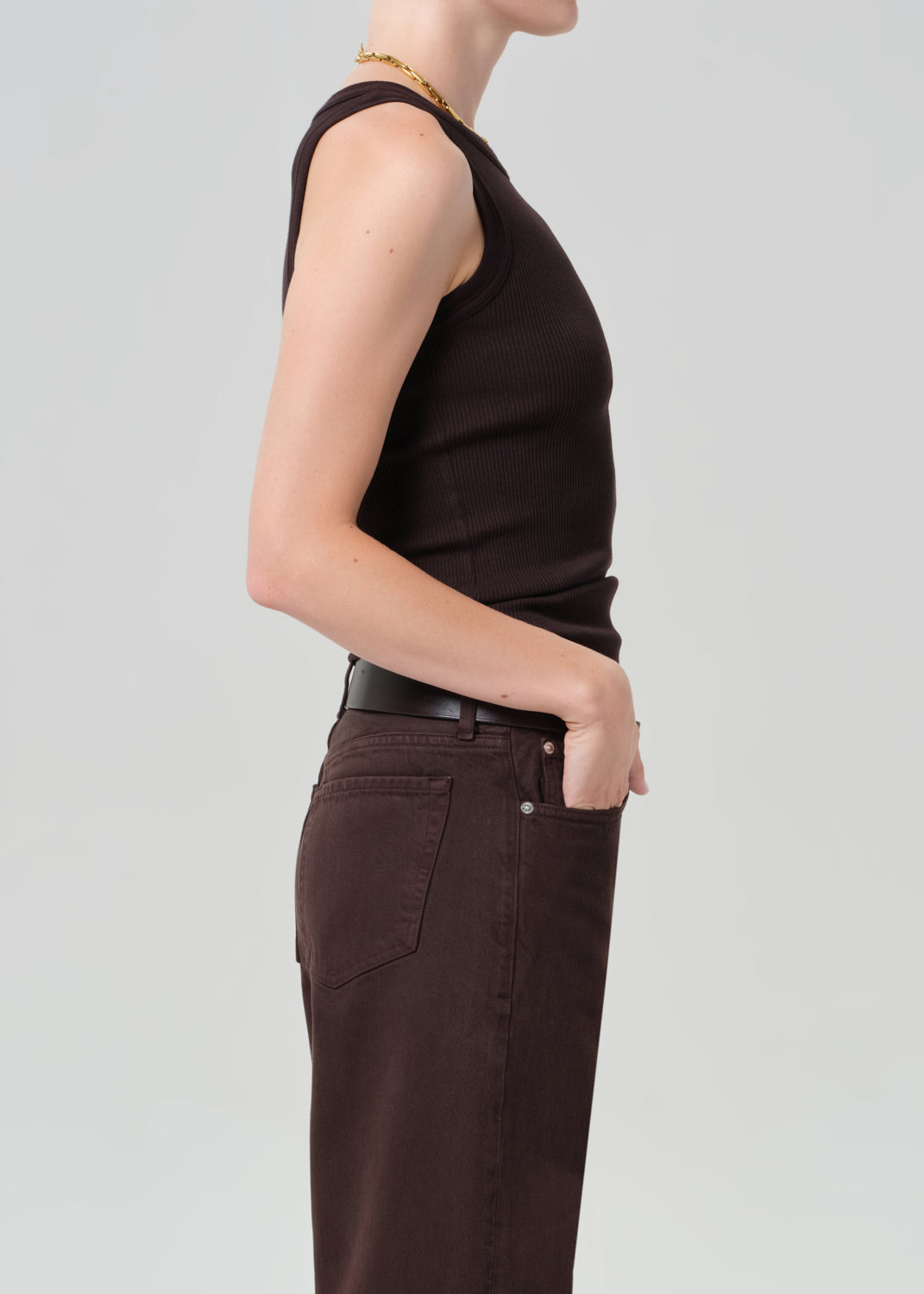 Person wearing a brown ribbed tank top with brown pants