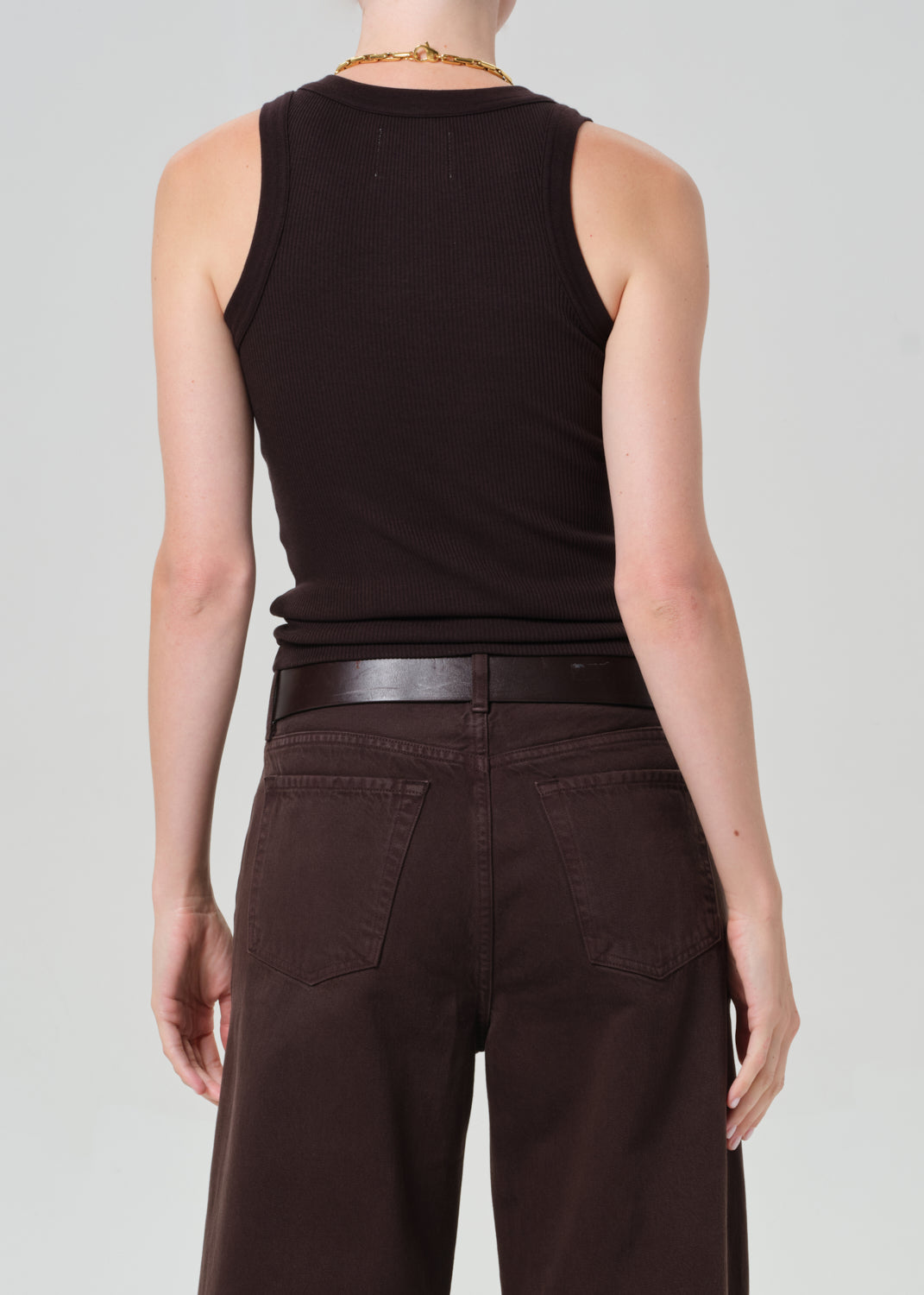 Person wearing a brown ribbed tank top with brown pants