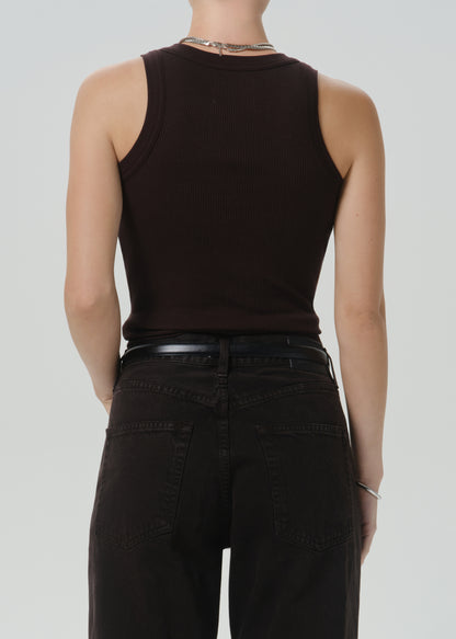 Rear view of a model wearing a dark brown ribbed sleeveless tank top and black jeans against a grey background.
