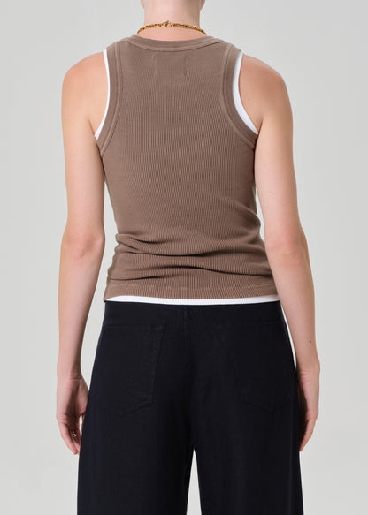 Person wearing a brown ribbed tank and navy pants on a gray background