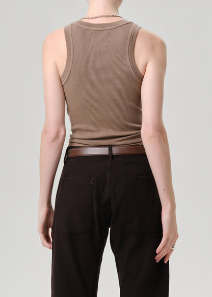 Rear view of a model wearing a ribbed brown tank top and dark brown pants with a matching belt, set against a grey background.
