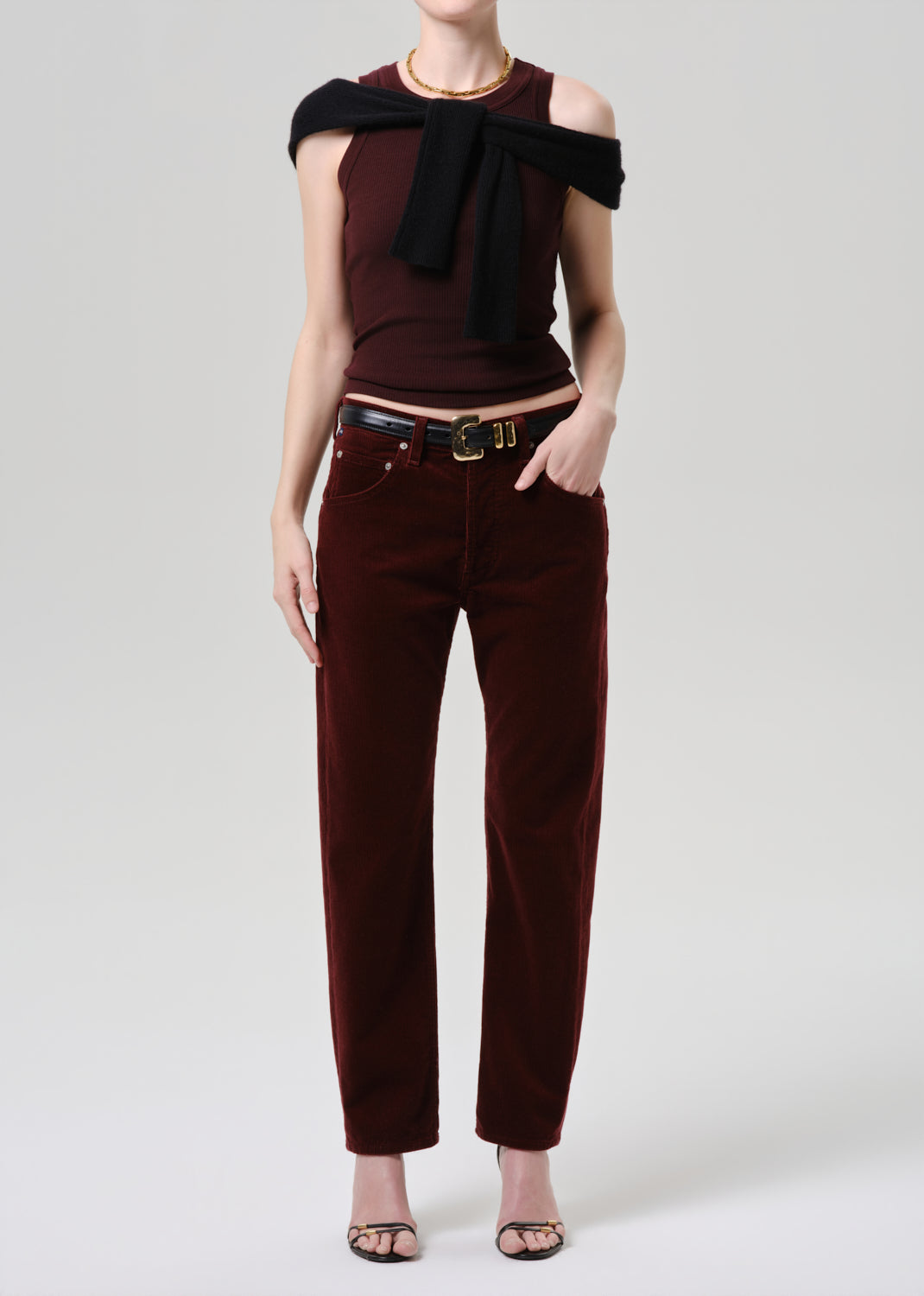 Person wearing a burgundy top with a bow detail and matching pants on a grey background