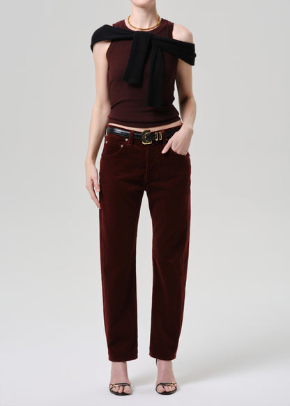 Person wearing a burgundy top with a bow detail and matching pants on a grey background