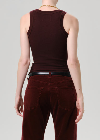 Rear view of a model wearing a dark burgundy ribbed tank top and matching burgundy corduroy pants with a black belt, against a grey background.
