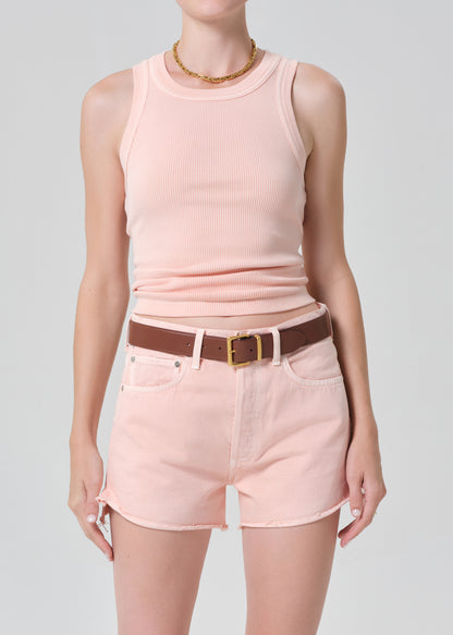 Person wearing a pink sleeveless top and shorts with a brown belt on a gray background
