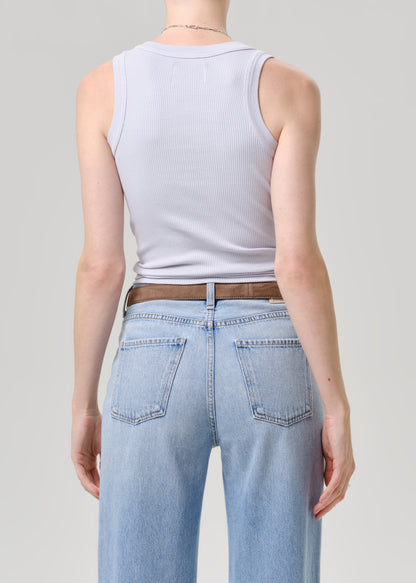 Person wearing a light blue tank top and light blue jeans on a grey background