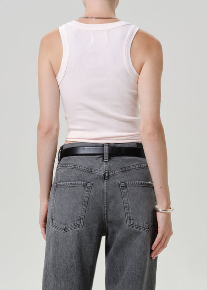 Rear view of a model wearing a pale pink ribbed tank top and gray jeans with a black belt, against a light gray studio background.