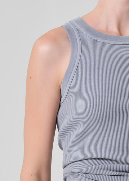 Close-up of a person wearing a ribbed tank top against a plain background