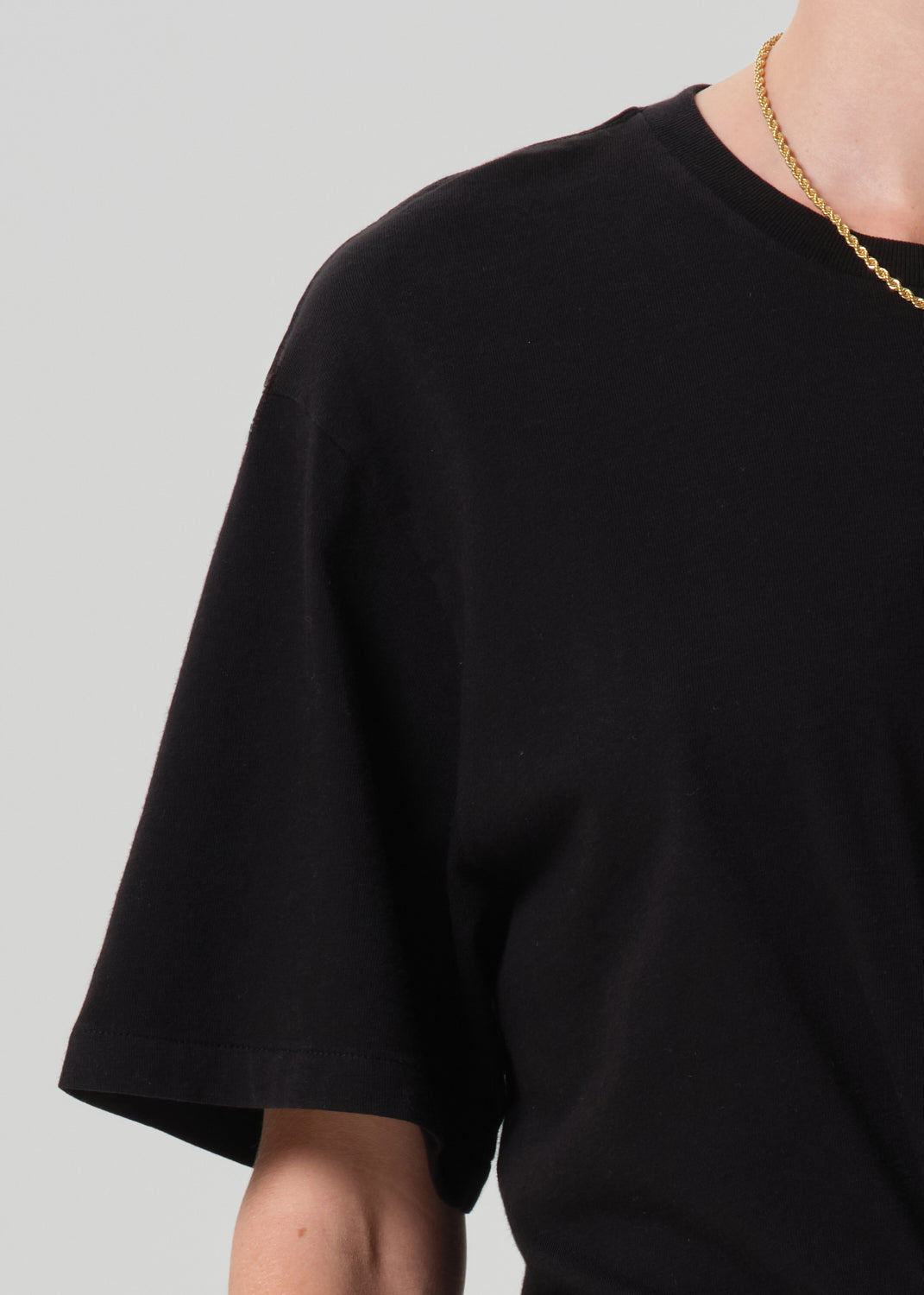 Close up of person wearing a black top on a grey background