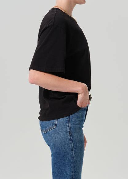 Person wearing black t-shirt with blue pants on a grey background
