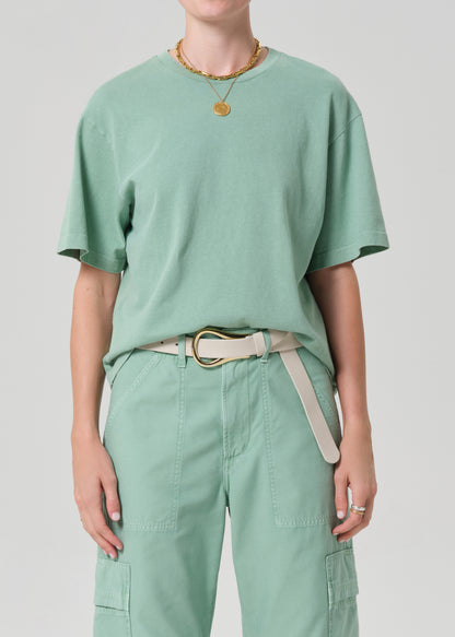 Person wearing a mint green t-shirt and pants with a belt on a light gray background