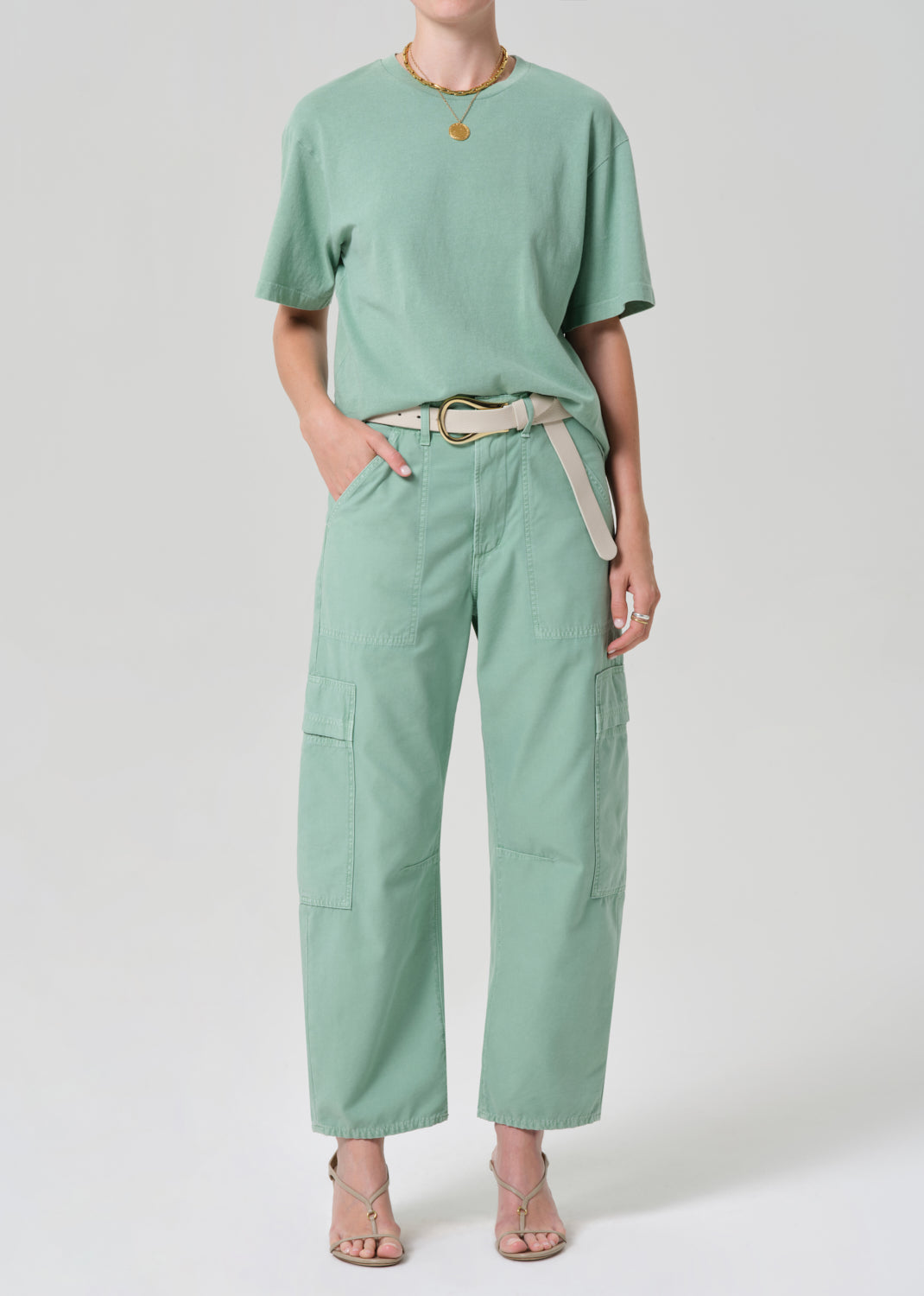 Person wearing a mint green outfit with cargo pants on a grey background