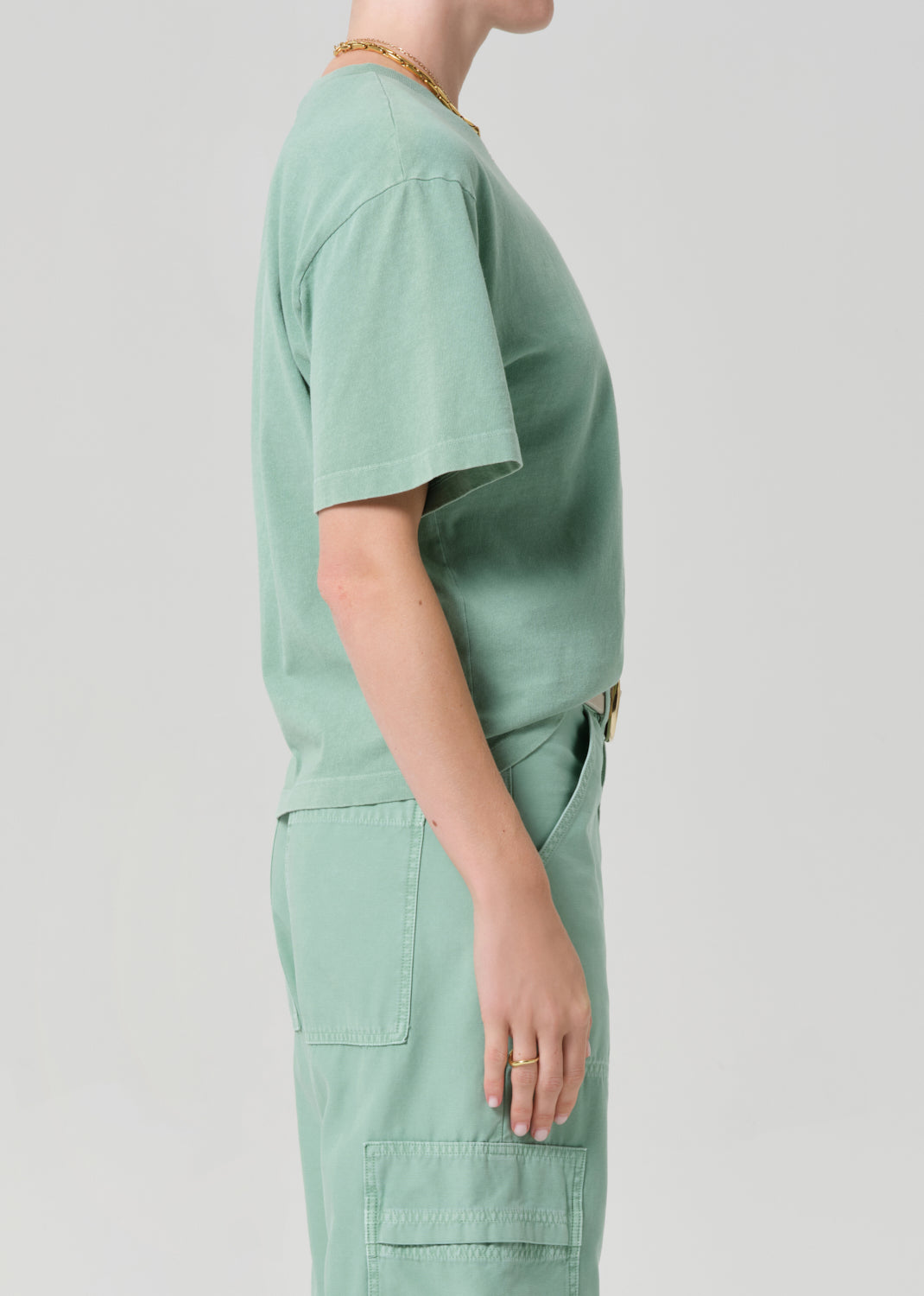 Person wearing a green scrub set on a light gray background