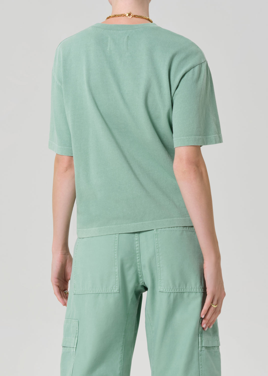 Person wearing a light green t-shirt and cargo pants on a plain background